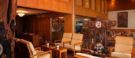 Un vestíbulo amplio con mobiliario de madera, una gran escultura de madera y una zona de bar.