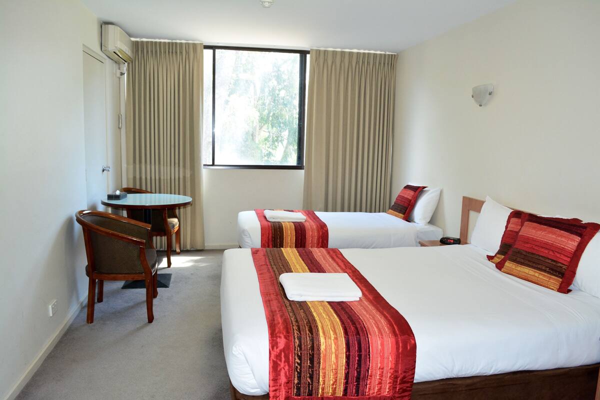 A hotel room with two beds, a desk, and a chair.