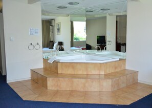 A modern bathroom with a large freestanding bathtub, a mirror, and a shower area. - City Park Hotel (South Melbourne)