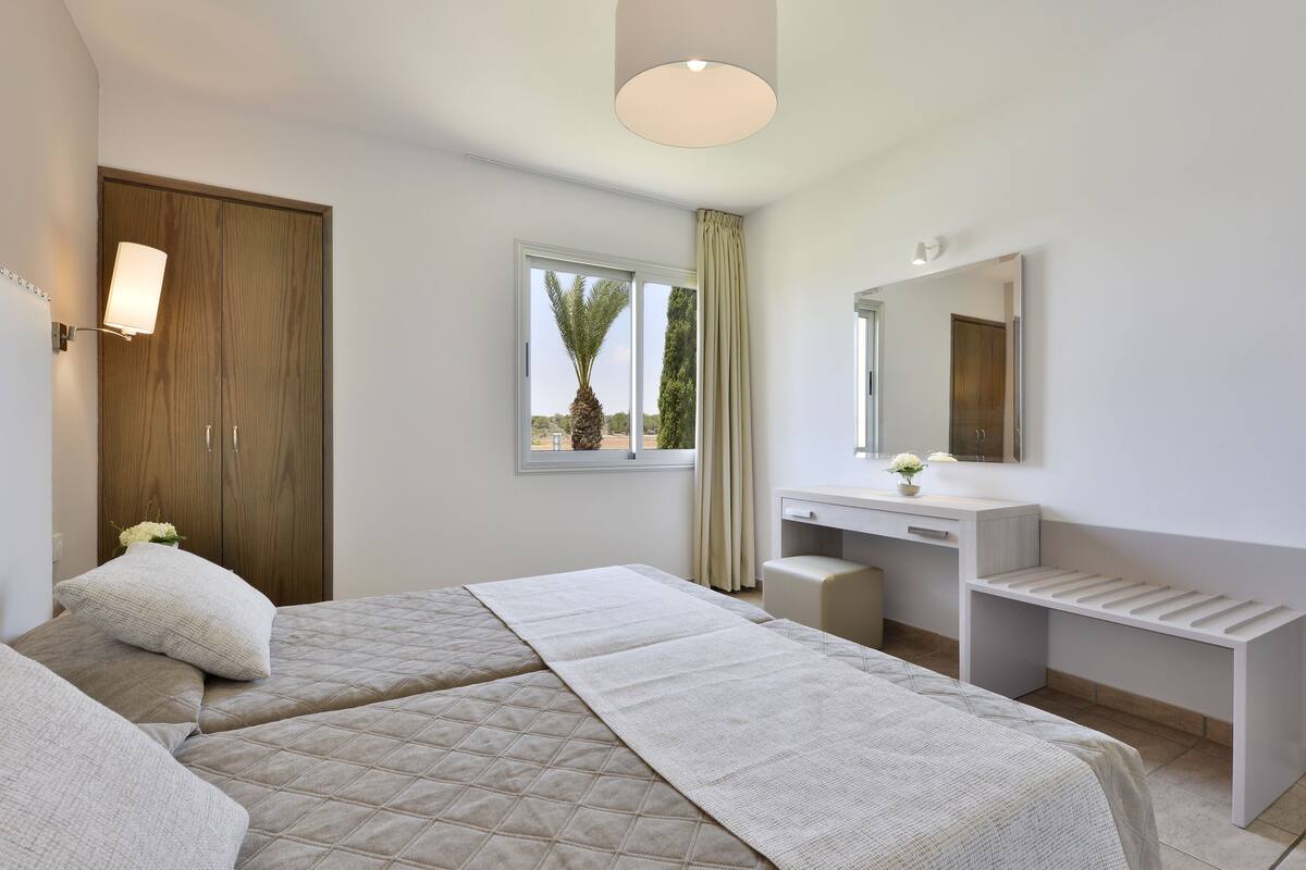 Une chambre avec deux lits, un bureau et une coiffeuse.