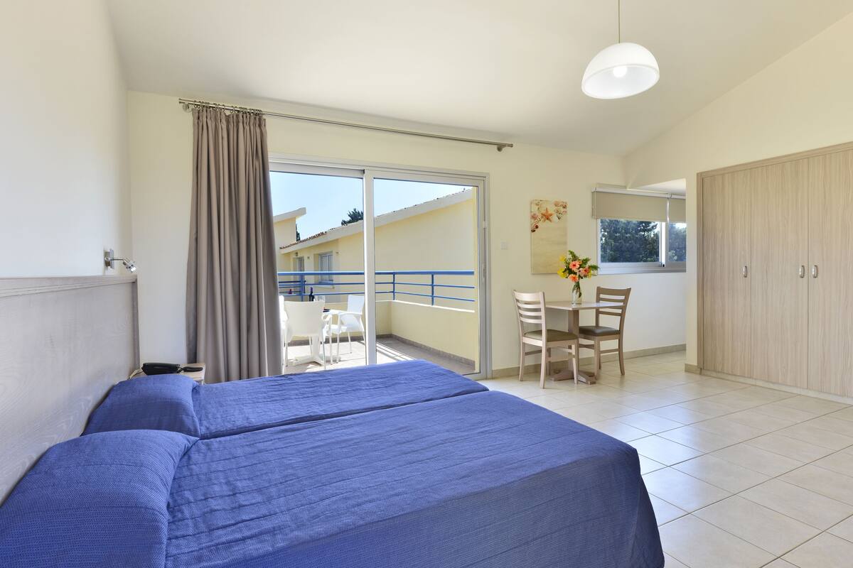 Une chambre d’hôtel avec un lit, un bureau et un balcon.