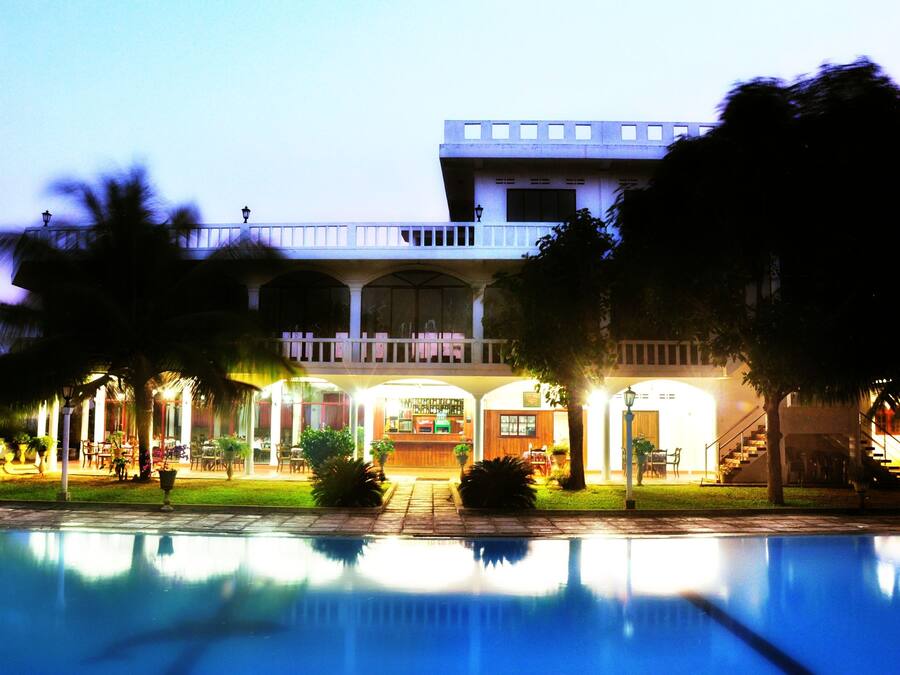 A hotel with a pool, a bar, and a covered outdoor seating area.