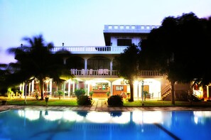 A hotel with a pool, a bar, and a covered outdoor seating area. - Hotel Lagoon Paradise (Negombo)