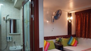 A hotel room with a shower, sink, two beds, a bedside table, a fan, and a window with curtains. - Delta Lounge (Kowloon)