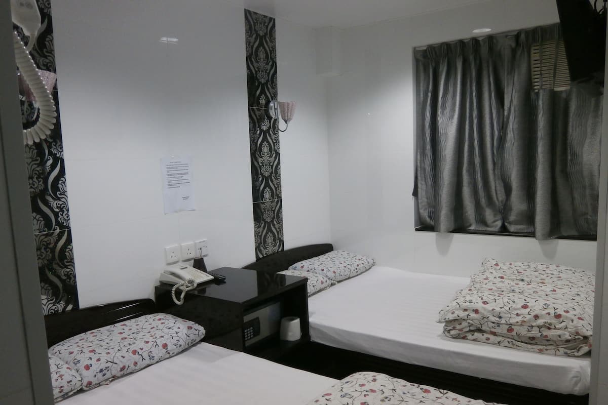 Quarto pequeno e compacto com duas camas de solteiro, uma escrivaninha com telefone e um espelho.