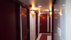 A hotel hallway with dark wooden doors, white tiled walls, and a marble floor. - Delta Lounge (Kowloon)