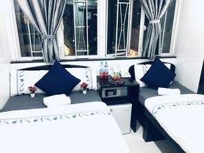 A hotel room with two beds, a small table with a microwave, and a window with curtains. - Ashoka Hostel (Kowloon)
