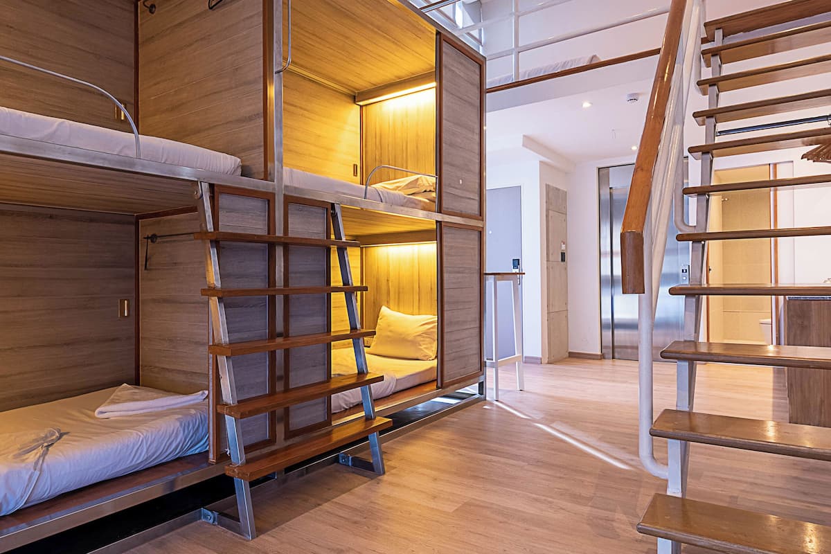A modern interior with bunk beds, a wooden staircase, and a bright, well-lit room.