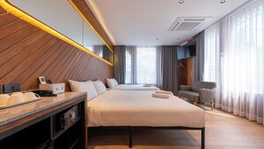 Una habitación de hotel moderna con una cama grande, un escritorio con teléfono y una televisión.