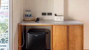 Una kitchenette compacta con refrigerador integrado, un televisor de pantalla plana sobre la encimera y un pequeño armario de madera.