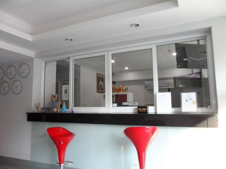 Una cocina moderna con un ventanal grande, una encimera negra y dos taburetes rojos.