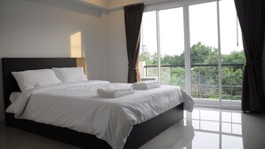 A modern hotel room with a large bed, a balcony with a view, and an air conditioning unit. - Delight Residence (Bangkok)