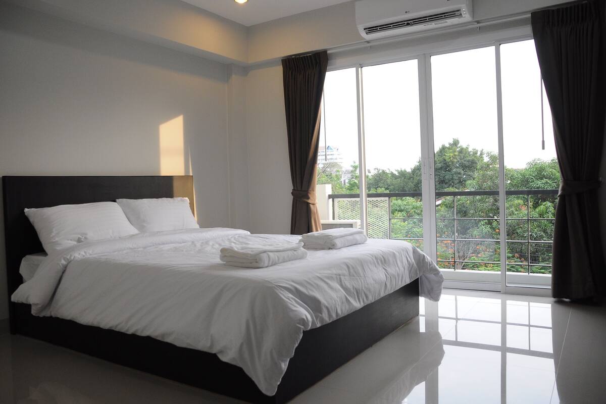 Una habitación de hotel moderna con una cama grande, un balcón con vistas y un equipo de aire acondicionado.