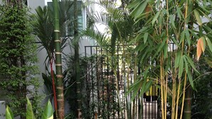 A landscaped garden with a stone pathway, various plants, and a building in the background. - Delight Residence (Bangkok)