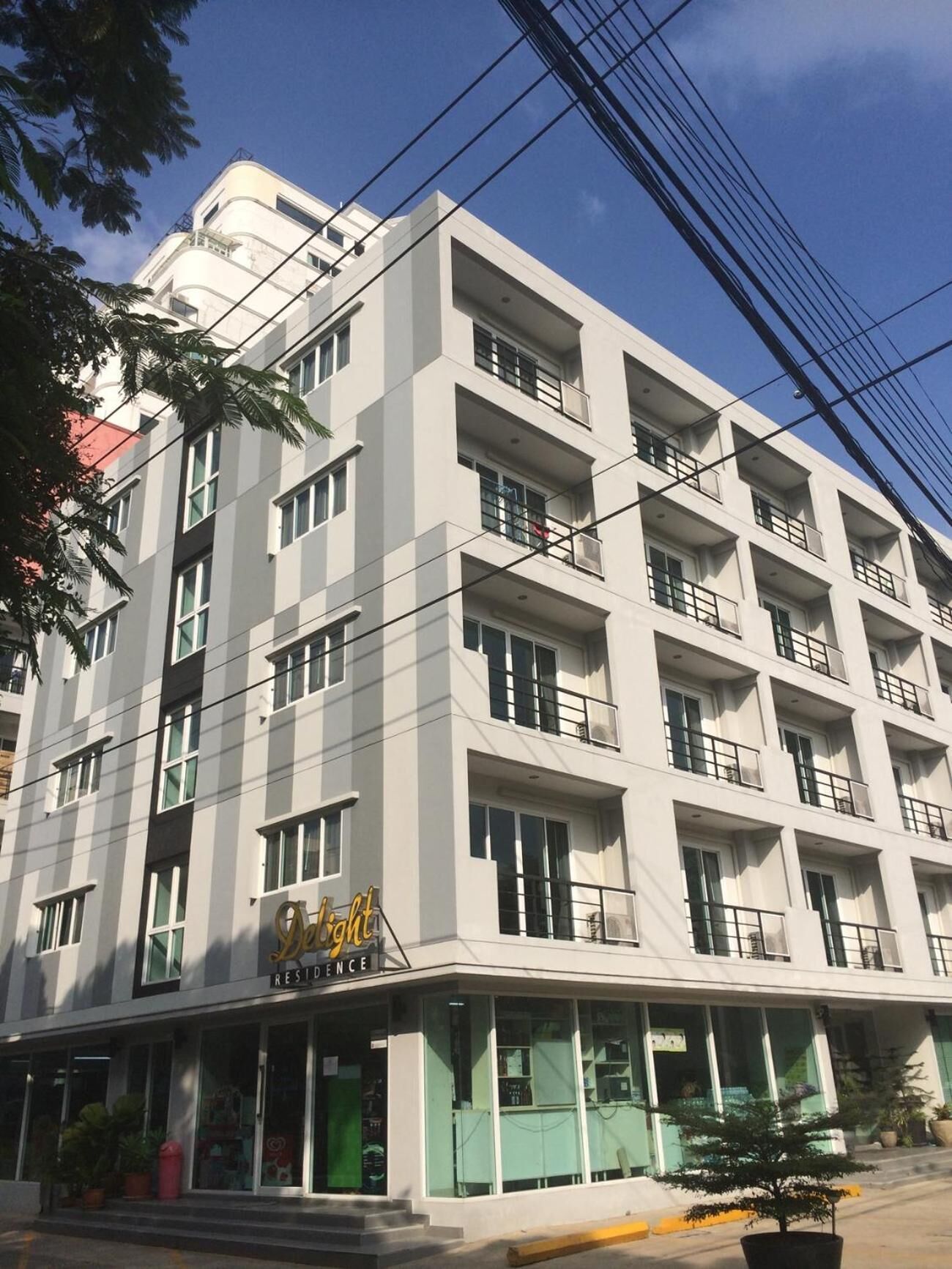 A multi-story hotel with a modern design, featuring balconies on each floor and a visible entrance with a sign.