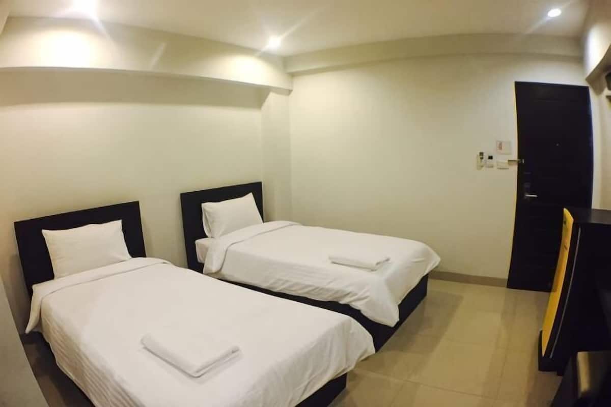 Habitación de hotel con dos camas, un escritorio y una puerta.