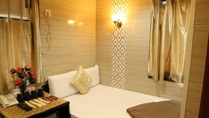 A hotel room with a bed, bedside table, lamp, and a wall-mounted light fixture. - Australian Guest House (Kowloon)