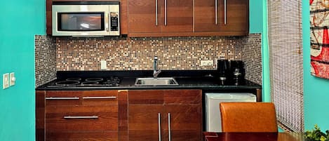 A compact kitchen with wooden cabinets, a microwave, a sink, and a coffee maker.