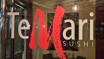A restaurant sign with the name "Telari Sushi" and a red abstract design.