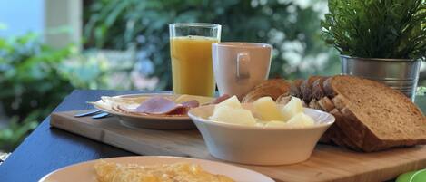 A breakfast table with a plate of eggs, toast, ham, and a glass of orange juice.