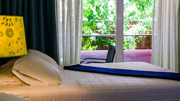 A bed with a blue mattress topper, white pillows, and a yellow floral-patterned lamp.