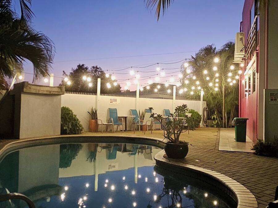 A swimming pool with a tiled edge, surrounded by lounge chairs and potted plants.
