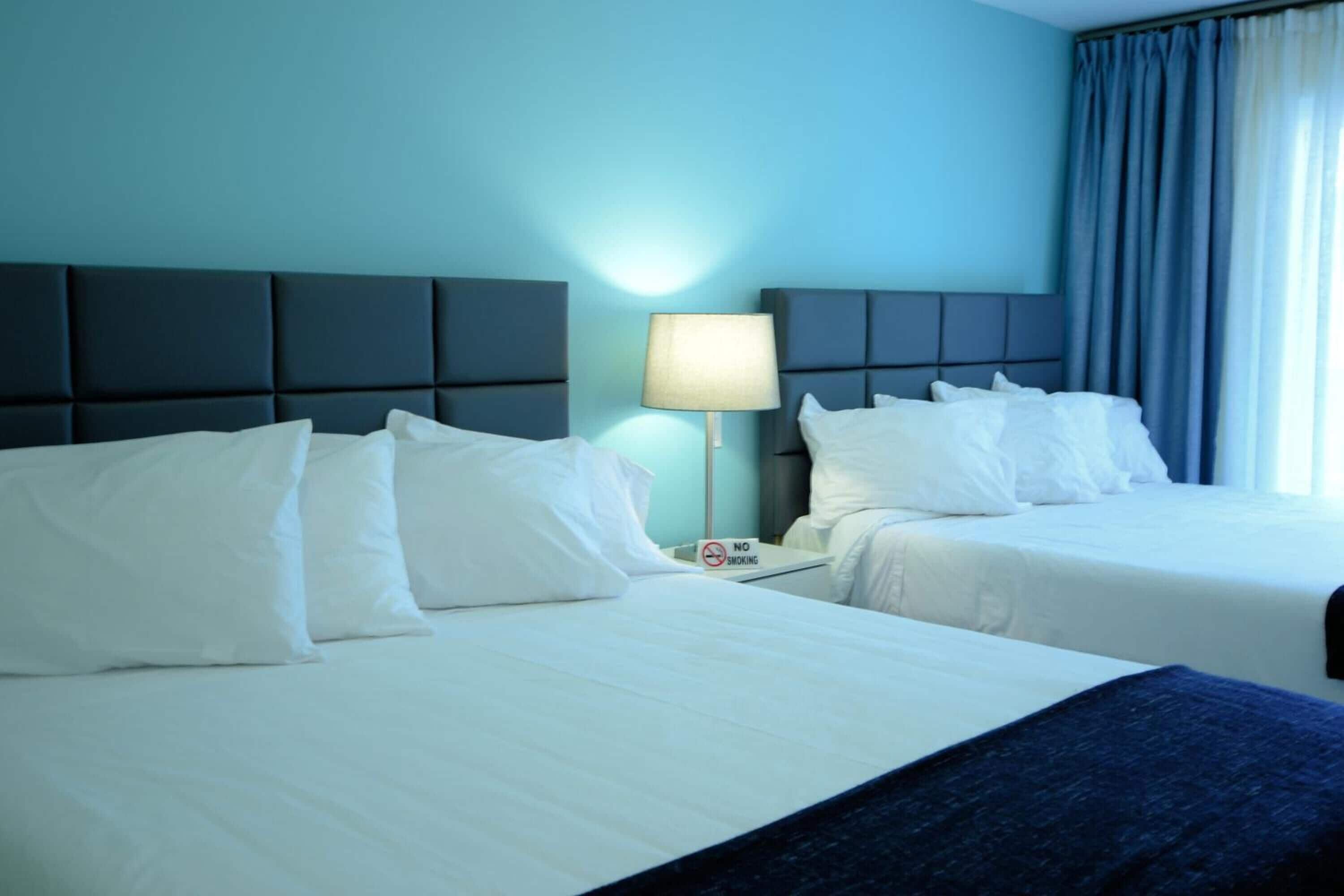 Ein Hotelzimmer mit zwei Betten, einem Nachttisch mit Lampe und einem Rauchverbot-Schild.