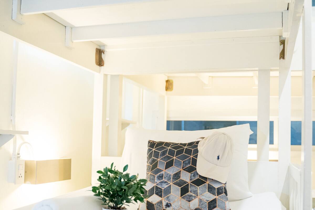 A hotel room with a bed, a pillow, a plant, and a towel.