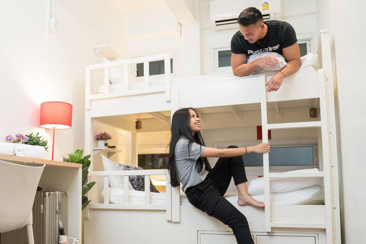 A bunk bed room with a desk and a lamp.