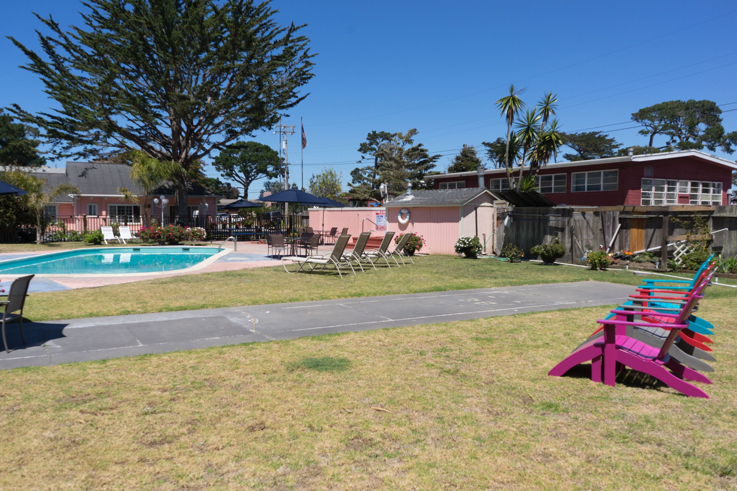 Ein Garten mit Schwimmbad, Liegestühlen und einer farbenfrohen Bank.