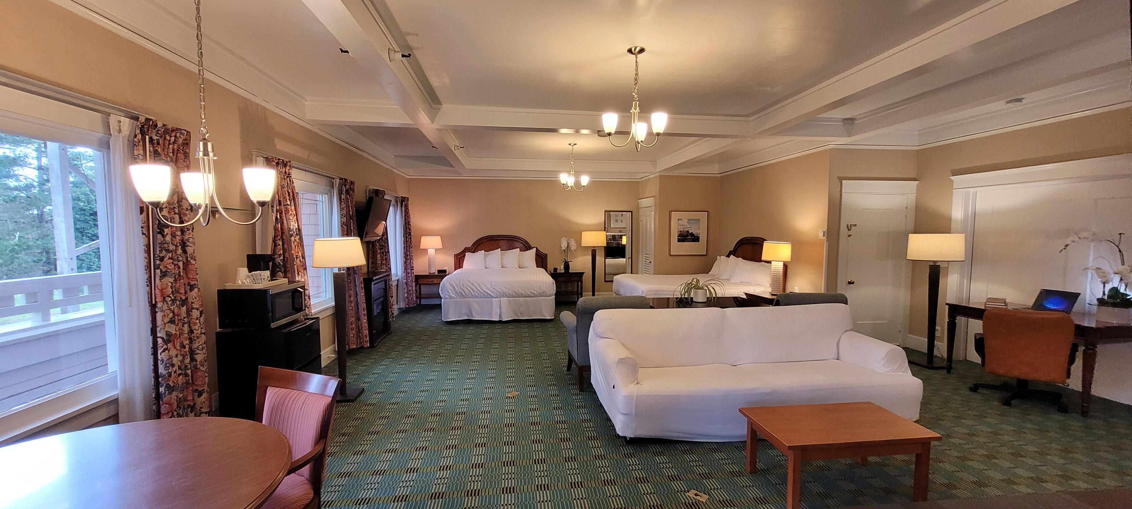 Une chambre d’hôtel avec un grand lit, un canapé, une table à manger et un bureau avec un ordinateur.