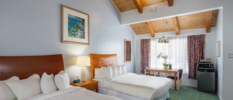 Une chambre d’hôtel avec deux lits, un plafond en bois, un tableau au mur, un bureau avec une chaise et un réfrigérateur.