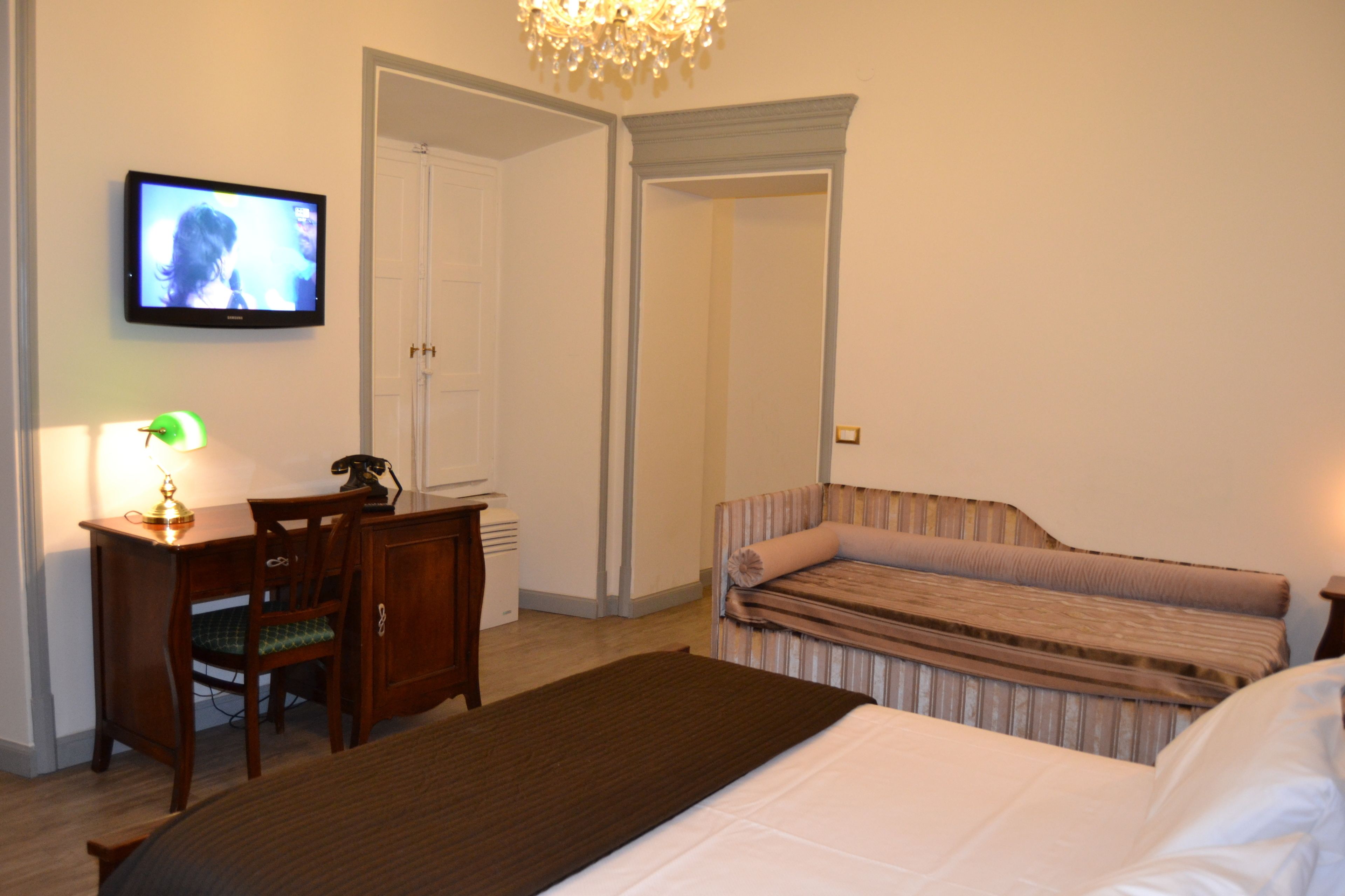 Une chambre d’hôtel avec un lit, un bureau avec une lampe, une télévision et une chaise.