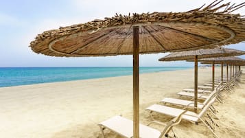 Aan het strand, ligstoelen aan het strand, parasols, een strandbar