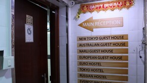 A wall with a sign listing various guest houses and a main reception direction. - Tokyo Hostel (Kowloon)