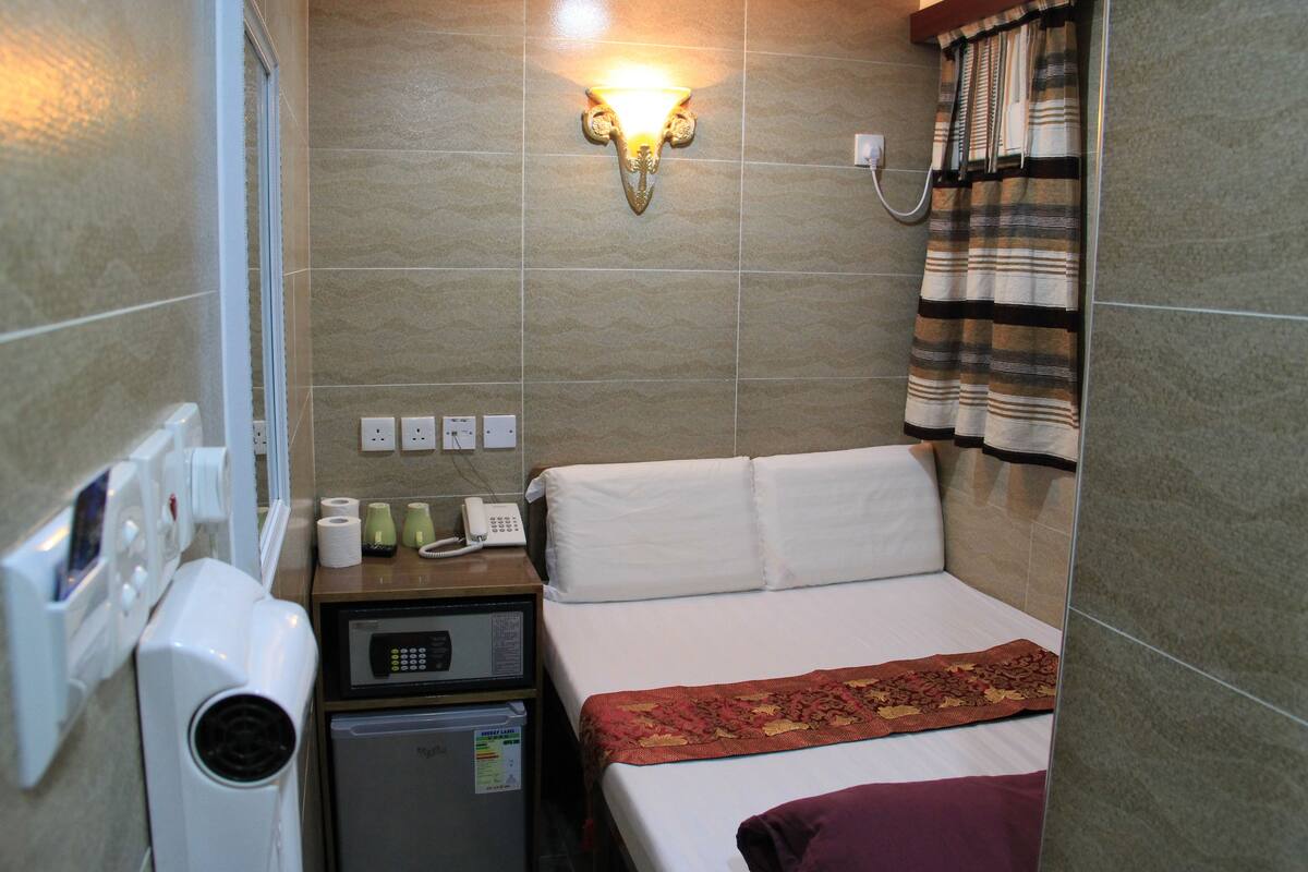 Une chambre d’hôtel équipée d’un lit, d’un petit réfrigérateur, d’un four à micro-ondes, d’un téléphone et d’une lampe fixée au mur.