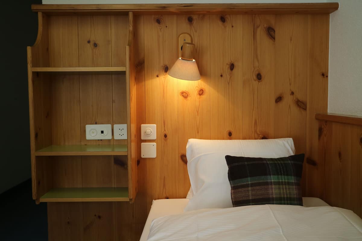 A wooden bunk bed with a nightstand and a lamp.