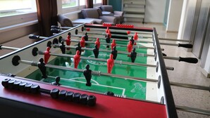 Uma mesa de futebol de mesa em um quarto com um sofá e uma janela.