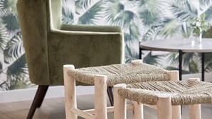 A room with a green armchair and two woven poufs.