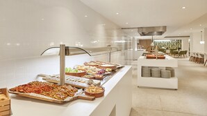 A buffet area with various food items, a white counter, and a seating area with chairs and tables.