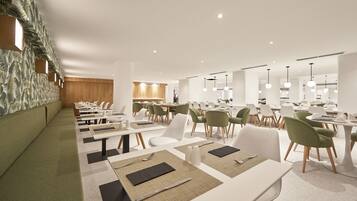 A modern dining area with white tables, green chairs, and a patterned wall.