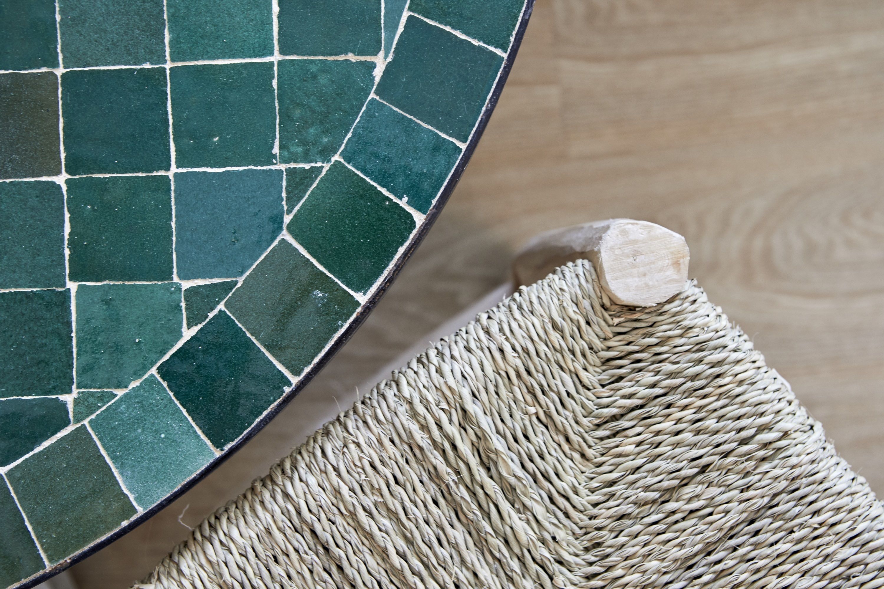 A close-up of a mosaic tile floor with a woven mat.