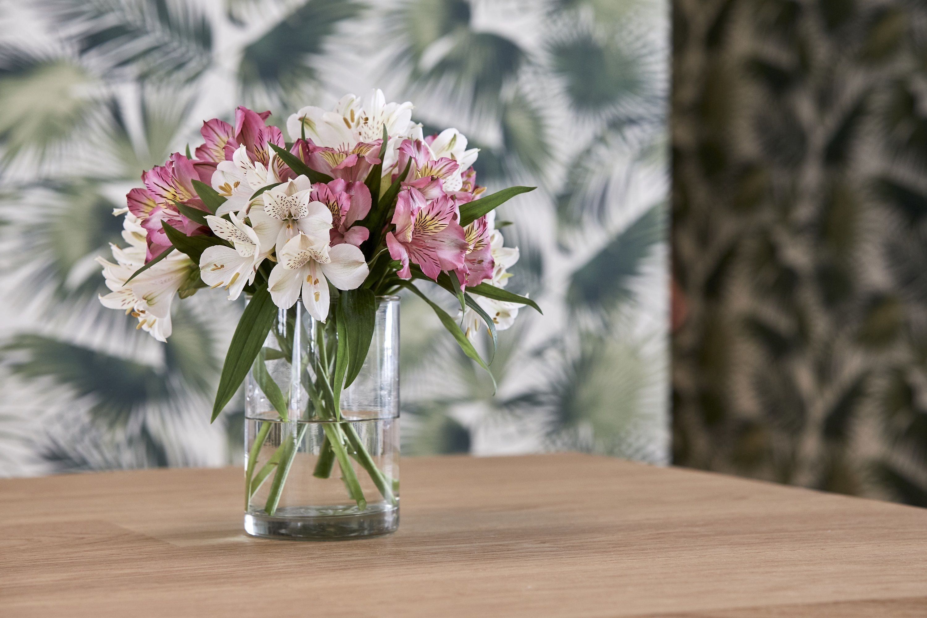 A clear glass vase with a bouquet of flowers on a wooden table.