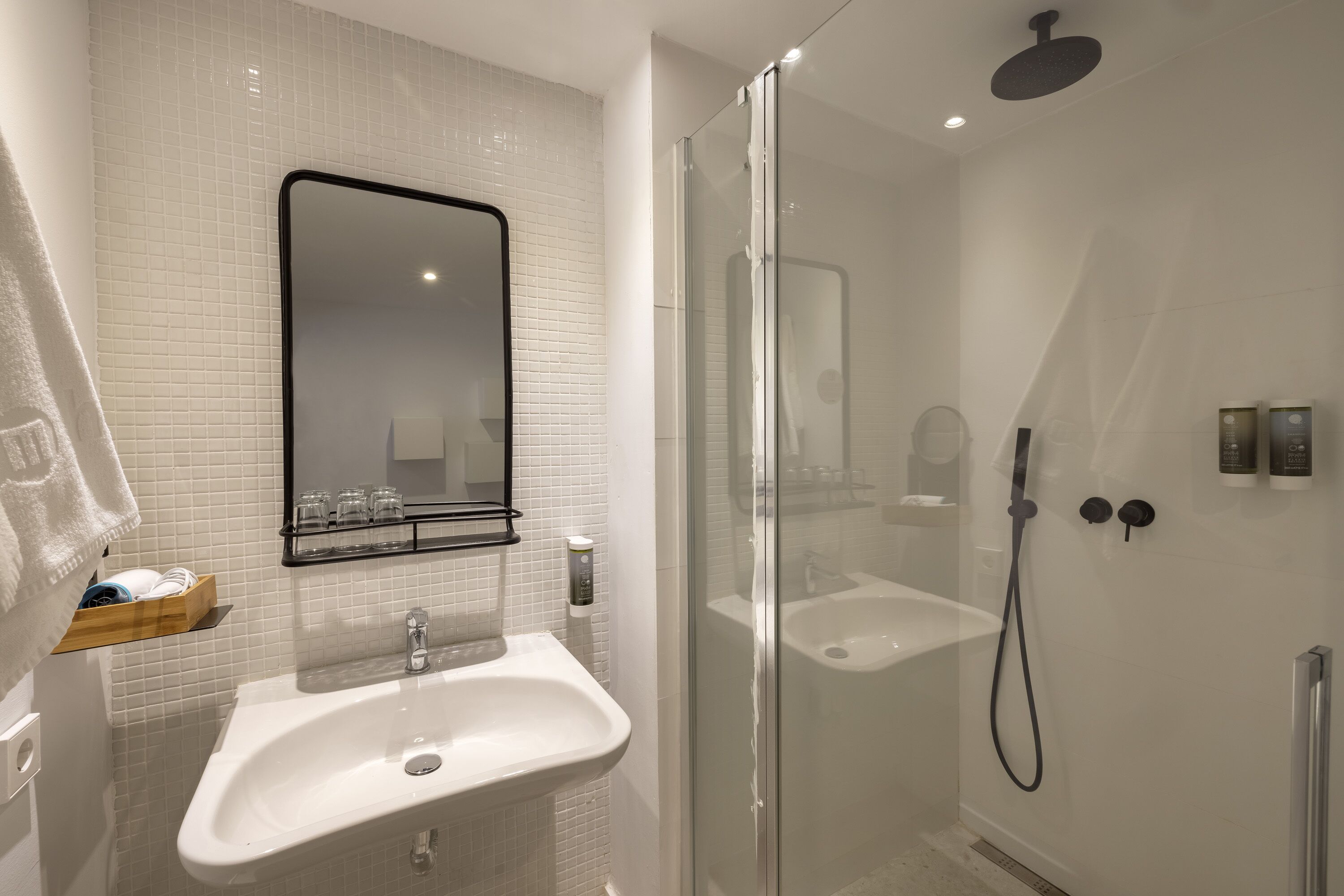 Een moderne badkamer met een douchekabinet van glas, een wit wastafelmeubel en een spiegel erboven.