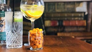 A table with two glasses of gin, one with a lemon slice, and a jar of nuts. - Mercure Thame Lambert Hotel (Watlington)