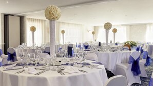 A banquet hall with round tables, white tablecloths, and blue chair covers. - Mercure Thame Lambert Hotel (Watlington)
