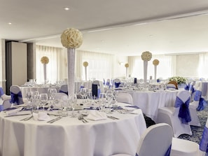 A banquet hall with round tables, white tablecloths, and blue chair covers. - Mercure Thame Lambert Hotel (Watlington)