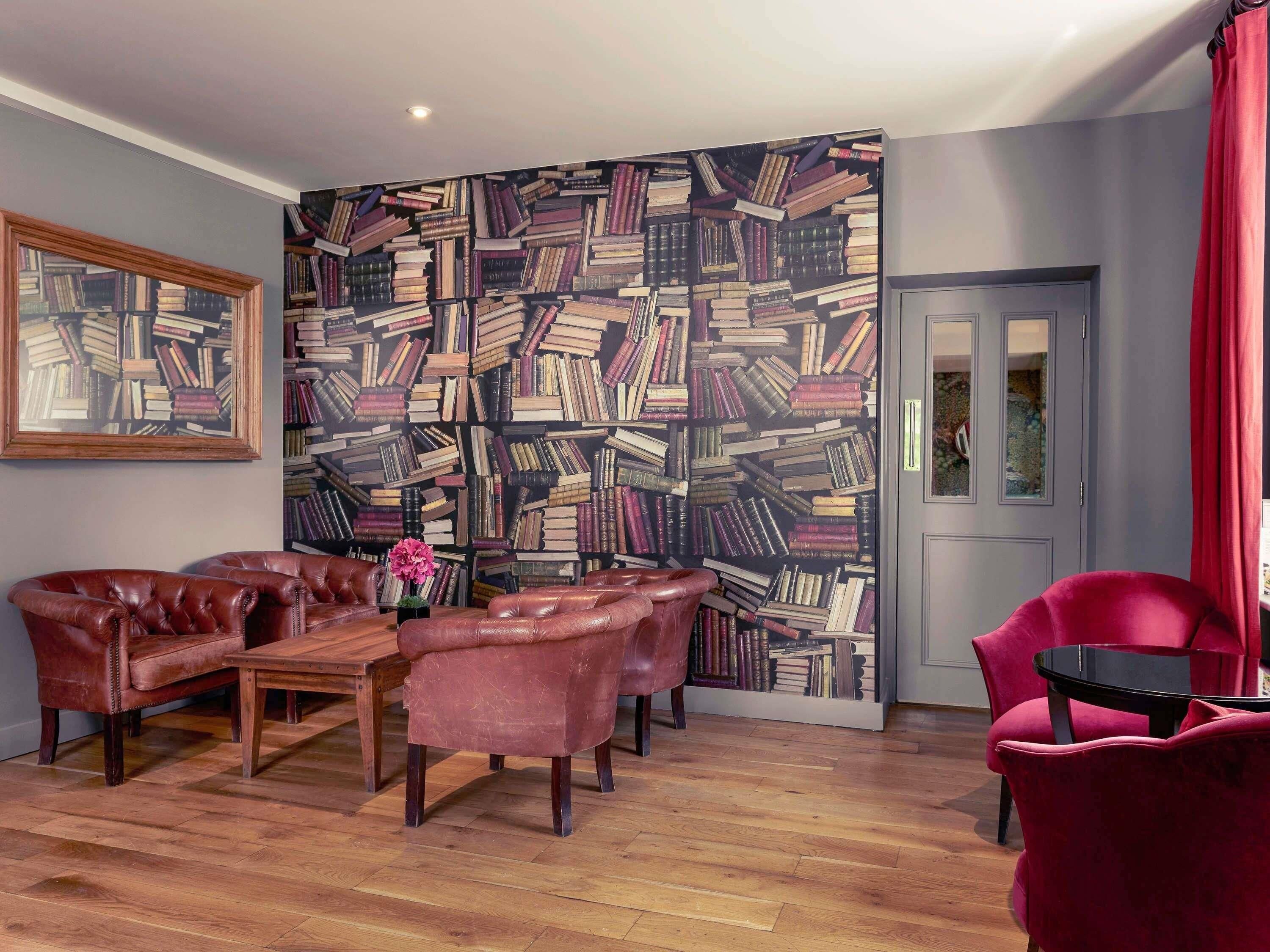 A room with a patterned wall, leather furniture, and a wooden floor.