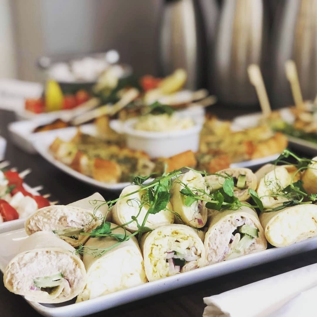 Une table de buffet proposant divers plats, notamment des wraps et des salades.