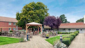 Un cortile con un gazebo, posti a sedere all'aperto e un vialetto in mattoni.